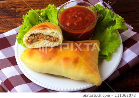 meat esfiha (sfiha) of Arab origin traditionally adapted for the Brazilian cuisine on plate on rustic wooden table meat esfiha (sfiha) of Arab origin traditionally adapted for the Brazilian cuisine on plate on rustic wooden table 111362078