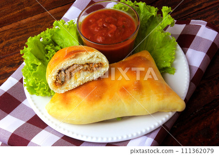 meat esfiha (sfiha) of Arab origin traditionally adapted for the Brazilian cuisine on plate on rustic wooden table meat esfiha (sfiha) of Arab origin traditionally adapted for the Brazilian cuisine on plate on rustic wooden table 111362079