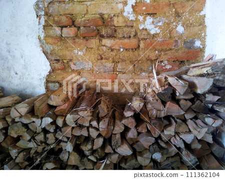 Firewood stack for winter to feed fireplace, with rustic wall background. 111362104