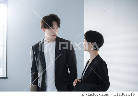 Conversation between a man and a woman wearing jackets and suits with computers 111362119