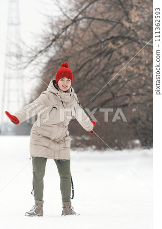 Portrait of a beautiful young woman in winter clothes walking in the park. Vertical frame 111362593