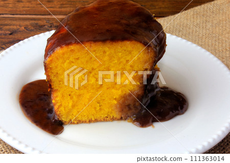 slice of carrot cake with chocolate coating on white ceramic plate on rustic wooden table slice of carrot cake with chocolate coating on white ceramic plate on rustic wooden table 111363014