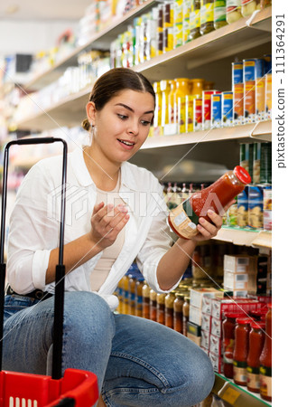 Young girl reading labels on bottles with juices in store Young girl reading labels on bottles with juices in store 111364291