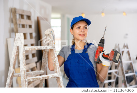 Portrait of young woman builder with drill Portrait of young woman builder with drill 111364300