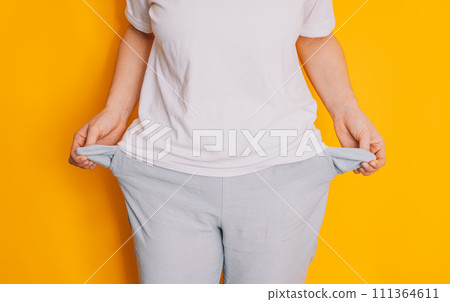 Lady turned out her empty pockets against a yellow background Lady turned out her empty pockets against a yellow background 111364611
