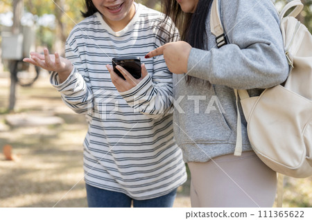 Two young happy Asian female college students are looking at a smartphone screen together 111365622