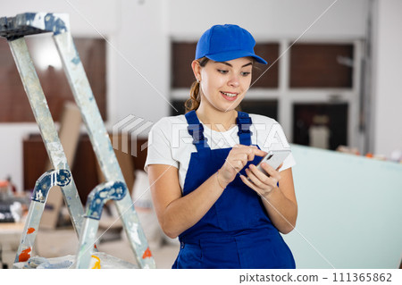 Young woman builder using smartphone in construction site 111365862