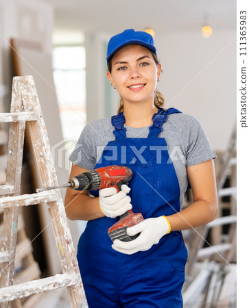 Portrait of young woman builder with drill 111365983