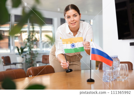 Employee of delegation prepares negotiating table - sets up flag of India and Russia Employee of delegation prepares negotiating table - sets up flag of India and Russia 111365992