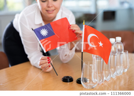 Woman secretary prepares an office for negotiations - she places flags of Taiwan and Turkish table 111366000