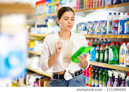 Interested young woman choosing household chemicals in store 111366004