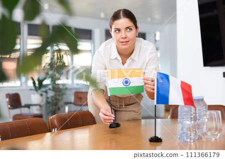 Employee of delegation prepares negotiating table - sets up flag of India and France 111366179
