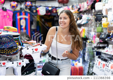Cheerful girl choosing souvenir panties with funny prints 111366398