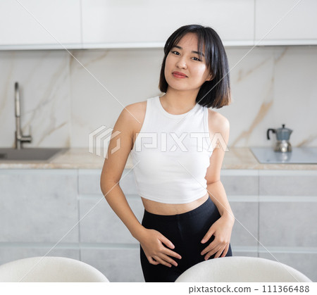 Smiling young Asian girl standing at table in the kitchen 111366488