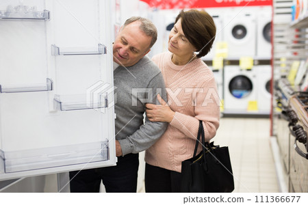 Senior couple choosing refrigerator in appliance store Senior couple choosing refrigerator in appliance store 111366677