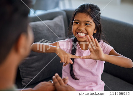 Child, sign language and learning to communicate with deaf girl or parent while making fingers and showing visual symbols at home. Happy kid with hearing disability or loss sitting with a tutor 111366925