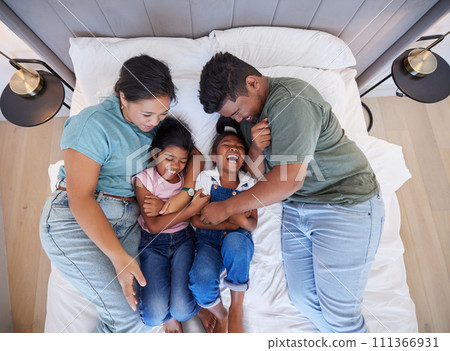 Family bed, home relax and parents in bedroom with children, care for comic kids and love in house together from above. Top view of girl siblings laughing with happy mother and father in the morning 111366931