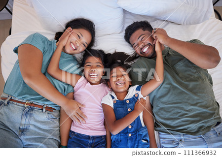 Happy family, love and morning smile with parents and children lying and playing in bed for fun together at home from above. Laugh, man and woman bonding with playful kids relax in bedroom with love 111366932