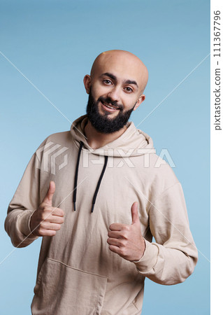 Cheerful arab man showing approval gesture with two thumbs up portrait. Smiling person with joyful facial expression standing with satisfaction sign while looking at camera Cheerful arab man showing approval gesture with two thumbs up portrait. Smiling person with joyful facial expression standing with satisfaction sign while looking at camera 111367796
