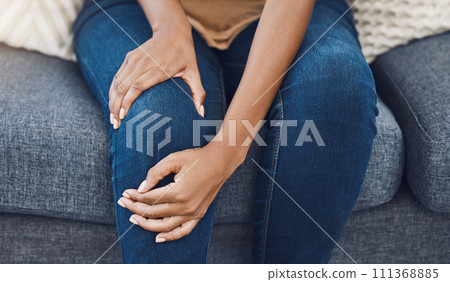 Black woman, hands and knee injury pain for person on house living room sofa or home interior lounge. Zoom on healthcare, wellness or medical surgery burnout, stress and legs muscle accident on couch Black woman, hands and knee injury pain for person on house living room sofa or home interior lounge. Zoom on healthcare, wellness or medical surgery burnout, stress and legs muscle accident on couch 111368885