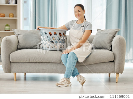Cleaning laundry, service and home woman working to clean basket of clothes, living room sofa and house linen in an apartment. Portrait of Asian cleaner staff in lounge doing housekeeping with smile Cleaning laundry, service and home woman working to clean basket of clothes, living room sofa and house linen in an apartment. Portrait of Asian cleaner staff in lounge doing housekeeping with smile 111369001