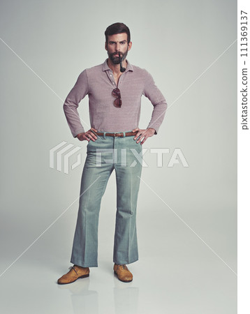 Retro, fashion and portrait of man with 70s vintage aesthetic in gray background of studio. Smoking, pipe and person with confidence and pride in funky clothes and unique style from past or history 111369137