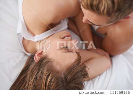 Couple, love and lying in bed, smile and romantic in hotel, celebrating and cuddle with intimacy. Above, bedroom and together in marriage, care and happy with affection, adoration and morning Couple, love and lying in bed, smile and romantic in hotel, celebrating and cuddle with intimacy. Above, bedroom and together in marriage, care and happy with affection, adoration and morning 111369156