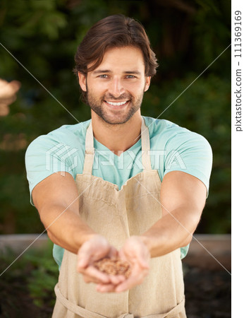 Man, hands together and seeds in portrait for sustainability, planting and growth in outdoor nursery. Male gardener, face and happy with grains for development, nurture and cultivation for future 111369169