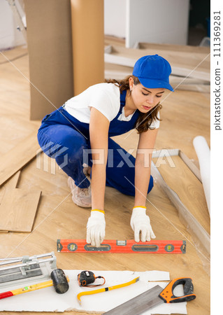 Female construction worker checking horizontal of floor with level 111369281