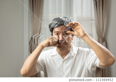 Senior man eye strain after for long stretches at computer or digital screens. 111369452