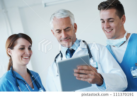 Tablet, team and doctor with nurses in hospital for medical diagnosis or treatment discussion. Meeting, digital technology and senior surgeon talk to healthcare workers for surgery research in clinic 111370191