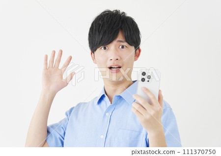 Surprised man holding a smartphone, white background, looking at camera 111370750