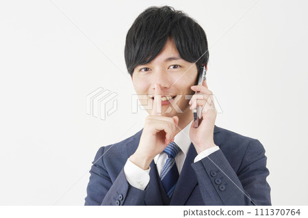 Businessman calling on smartphone while posing in a secret pose, white background 111370764