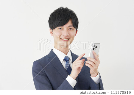 Businessman using smartphone, white background, looking at camera 111370819