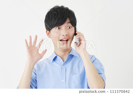 Surprised man calling on smartphone, white background Surprised man calling on smartphone, white background 111370842