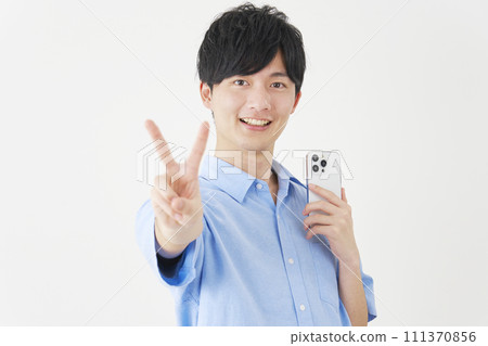 A man holding a smartphone and making a peace sign, white background 111370856