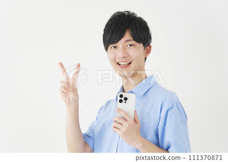 A man holding a smartphone and making a peace sign, white background A man holding a smartphone and making a peace sign, white background 111370871