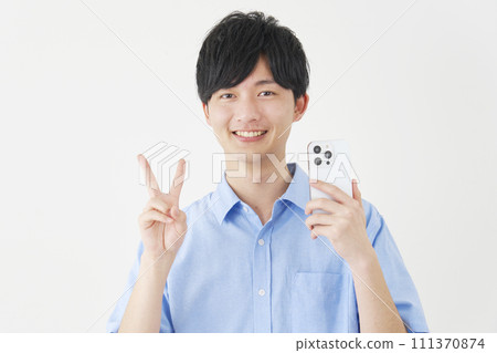A man holding a smartphone and making a peace sign, white background 111370874