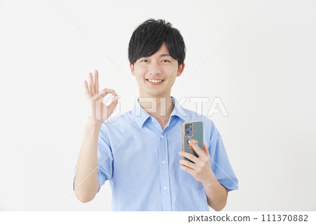 A man holding a smartphone and giving an OK sign, white background 111370882
