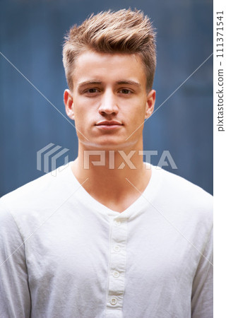 Portrait, serious and young man with style on a wall background in the city. Relax, face and caucasian male person in a casual tshirt with trendy, cool fashion from New Zealand with confidence 111371541