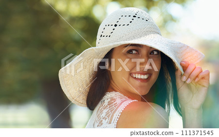 Woman, travel and freedom in park or garden, smile and joy on summer holiday. Female person, peace and enjoy vacation in countryside, outdoors and hat for protection on weekend adventure in nature 111371545