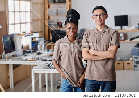 Biracial workshop employees in uniform confidently posing at their workplace and smiling at camera Biracial workshop employees in uniform confidently posing at their workplace and smiling at camera 111372001