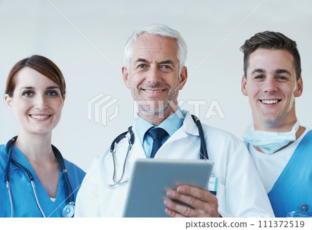 Tablet, smile and portrait of doctor with nurses in hospital for medical diagnosis or treatment discussion. Team, digital technology and senior surgeon with healthcare workers for surgery in clinic. Tablet, smile and portrait of doctor with nurses in hospital for medical diagnosis or treatment discussion. Team, digital technology and senior surgeon with healthcare workers for surgery in clinic. 111372519