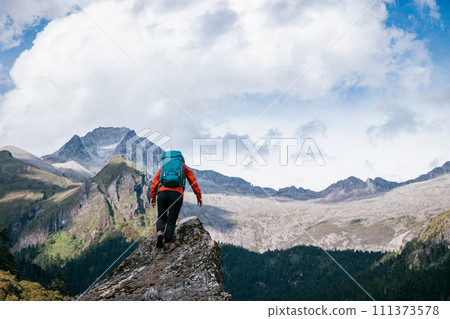 Woman hiker climbing to mountain top in tibet Woman hiker climbing to mountain top in tibet 111373578
