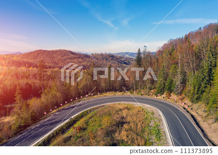 Hard turn on a winding highway in the autumn mountains. Drone view. Beautiful natural landscape. The Carpathians. Ukraine Hard turn on a winding highway in the autumn mountains. Drone view. Beautiful natural landscape. The Carpathians. Ukraine 111373895