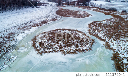 Aerial view of the frozen brook in winter. The texture of icy creek. Nature background Aerial view of the frozen brook in winter. The texture of icy creek. Nature background 111374041