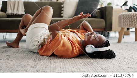 Music, headphones and black woman on floor, listening to song and audio in living room. Happy African person on radio, streaming sound and technology for freedom, relax on carpet and smile in home Music, headphones and black woman on floor, listening to song and audio in living room. Happy African person on radio, streaming sound and technology for freedom, relax on carpet and smile in home 111375764