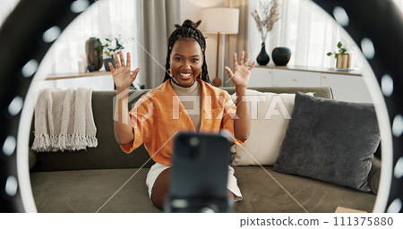 Wave, live streaming and happy black woman with box or product in home living room. Hello, influencer and person with package, record video on social media and content creation, ring light and phone Wave, live streaming and happy black woman with box or product in home living room. Hello, influencer and person with package, record video on social media and content creation, ring light and phone 111375880