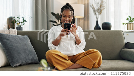 Home, funny and black woman on a sofa, cellphone and connection with social media, comedy post and laugh. African person, apartment or girl on couch, smartphone or mobile user with humor or typing 111375923