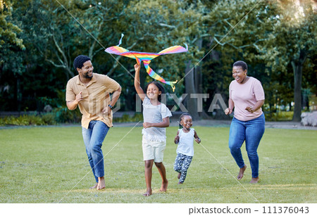 Black family, kite and outdoor fun with parents and children having fun and playing outside at a park in nature. Energy, love and running while being active and bonding with man, woman and kids 111376043